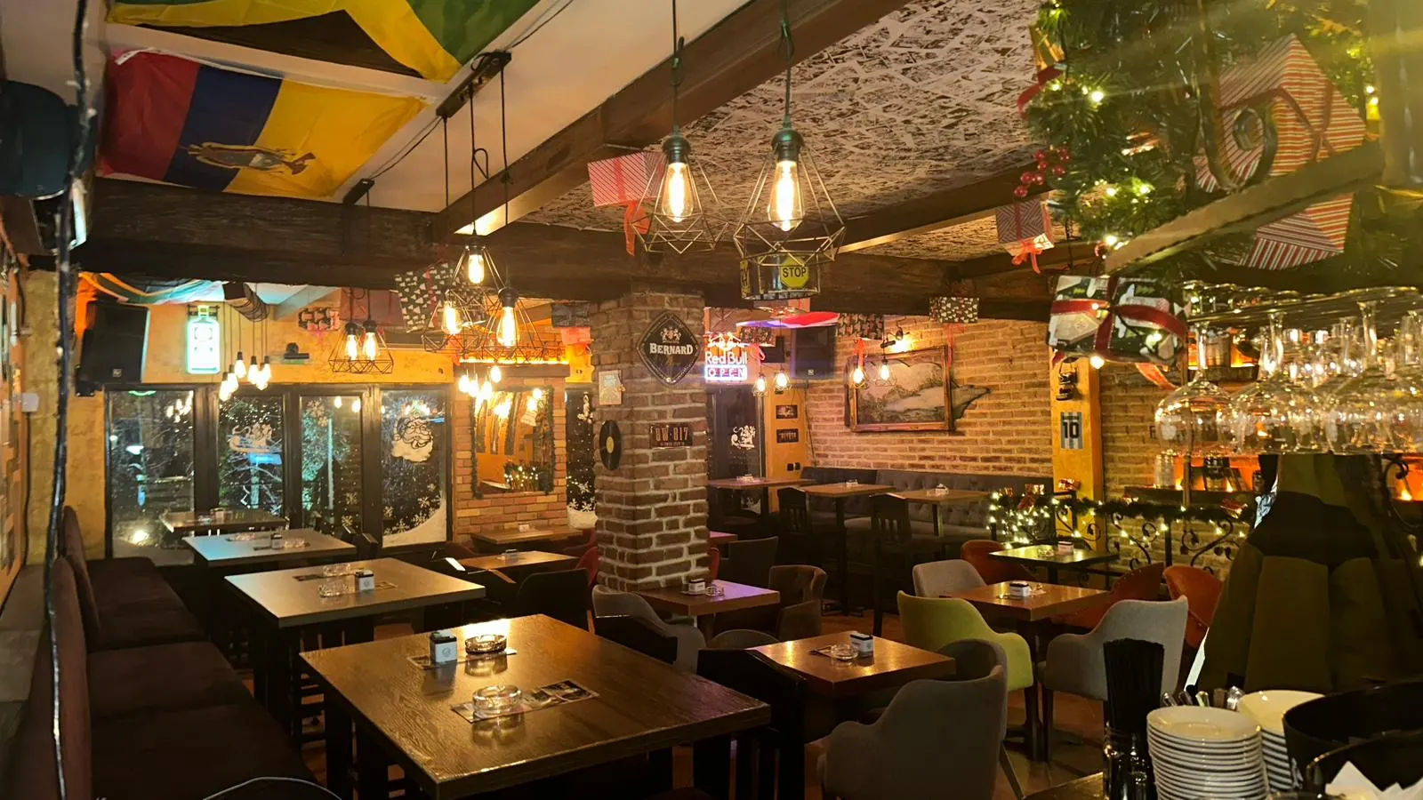 Sala sa drvenim stolovima, ciglom i visećim sijalicama