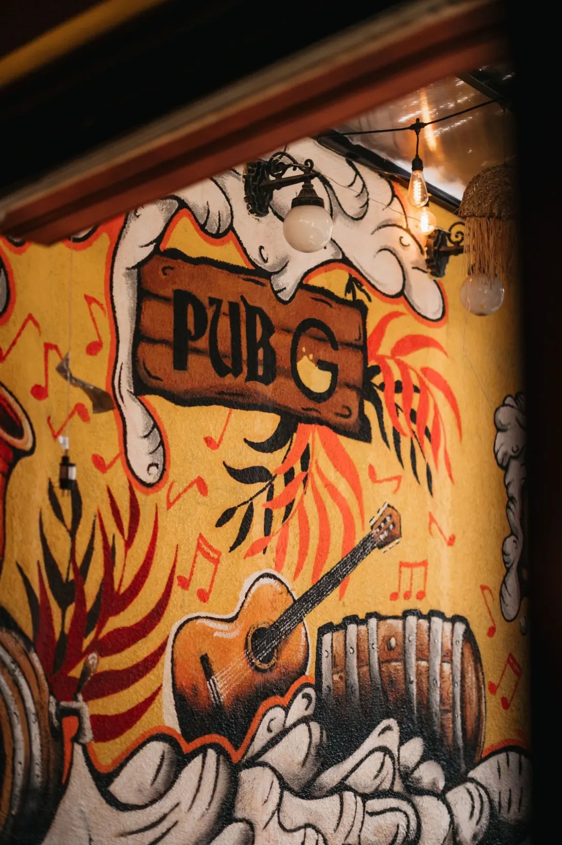 Oslikani zid sa natpisom PUB G, gitarom i buretom