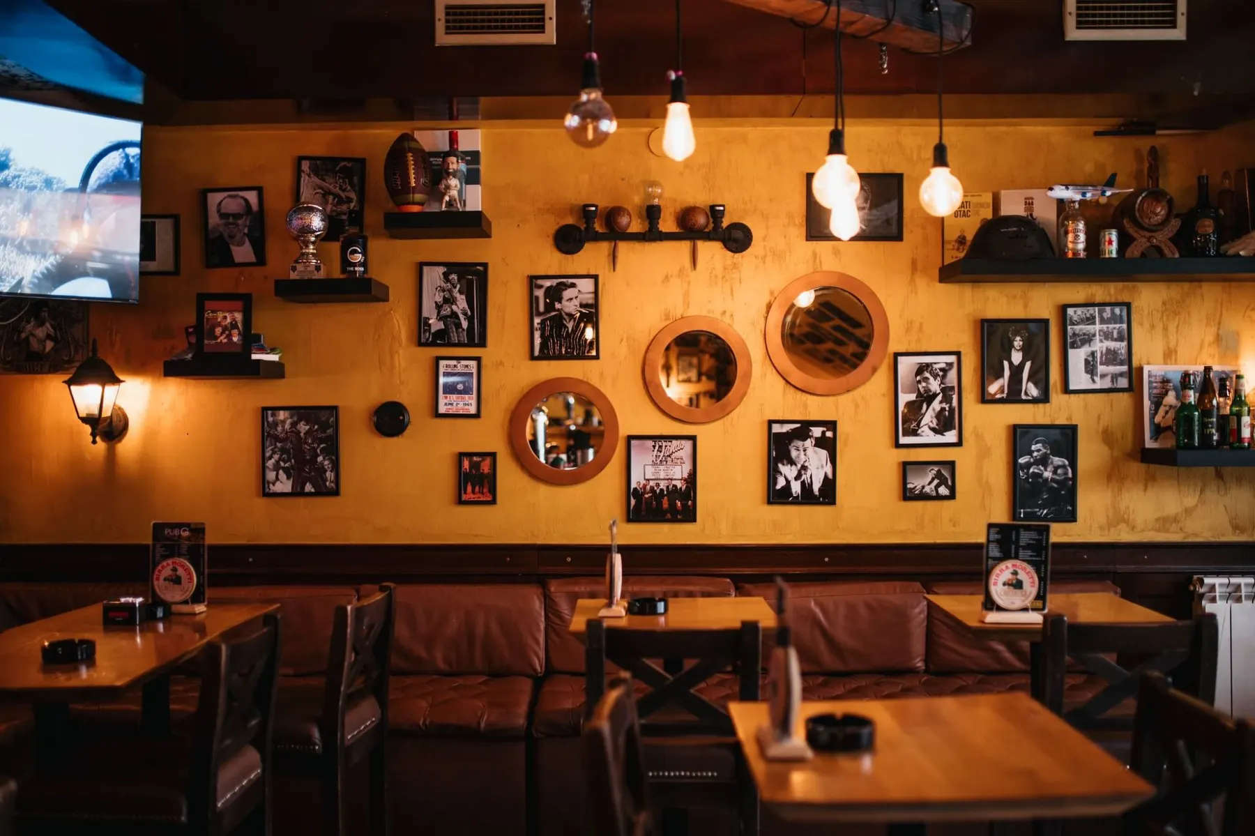 Žuti zid sa crno-belim fotografijama i okruglim ogledalima